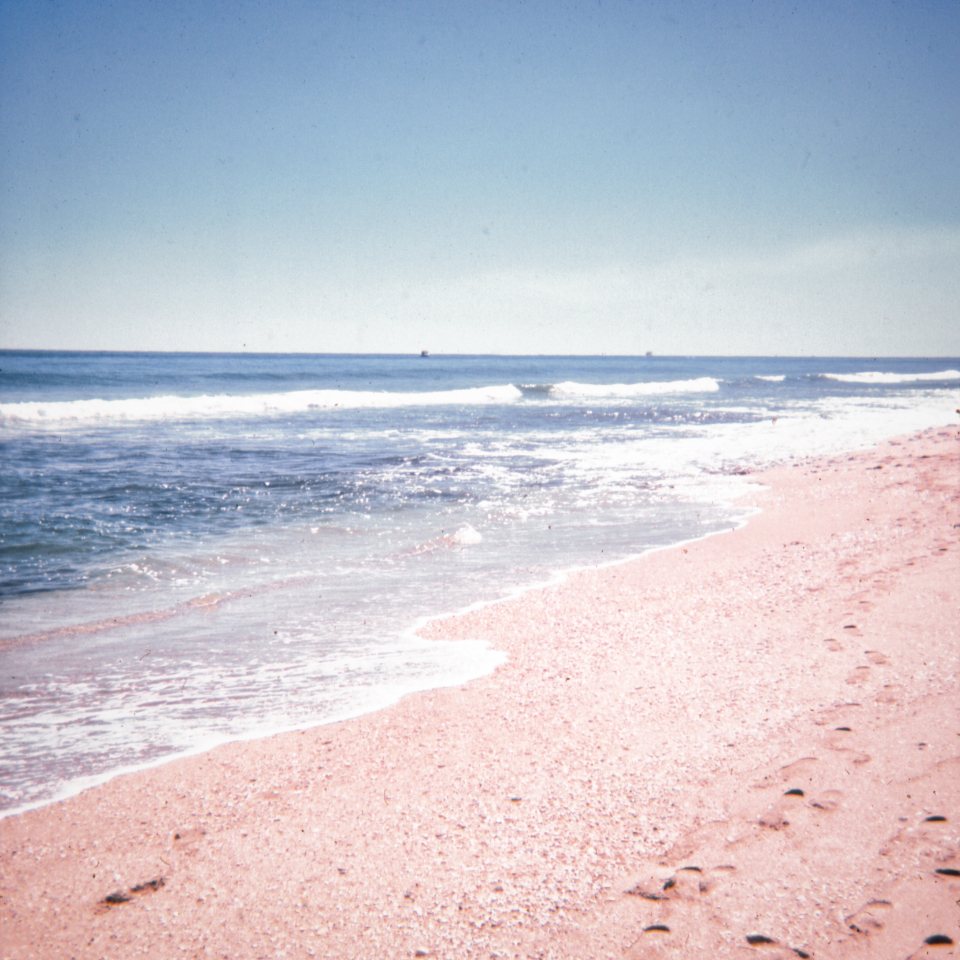 Sunlit waves washing onto a pale sandy beach