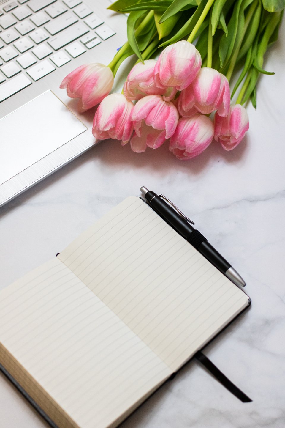 Open lined notebook and black pen on a light desk